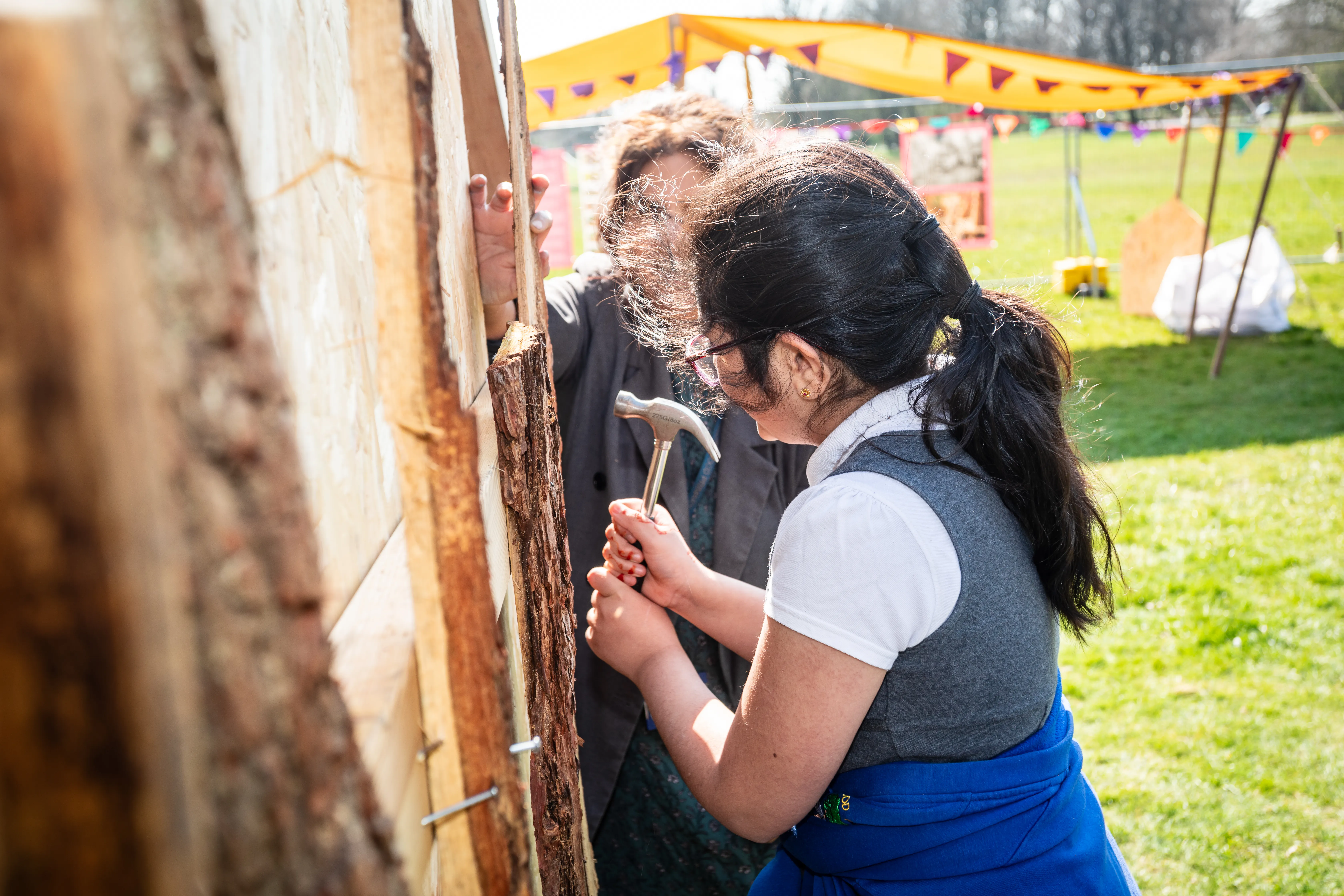 child hammering a nail into a wooden structure